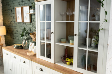 Eco style in the interior of the kitchen. Decor of a white sideboard with fruits and dishes.