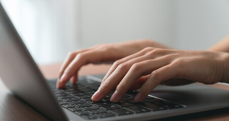 Hand using computer laptop and touching mouse on the table.