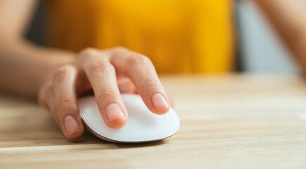 Hand using white mouse on the wood table.