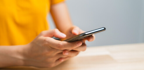 Hand holding smartphone with using social media on internet on table.