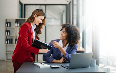 Two  businesswoman discuss investment project working and planning strategy with tablet laptop computer in modern office.