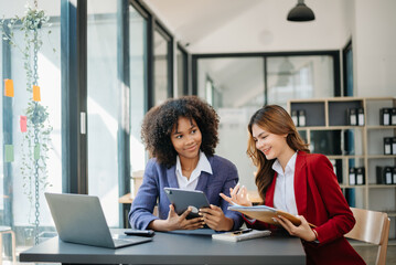 Two  businesswoman discuss investment project working and planning strategy with tablet laptop computer in modern office.