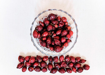 Dried red rose hips (berry, fruit) in glass jar on white background