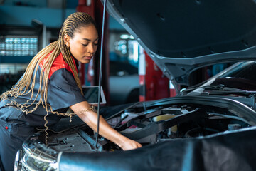 Auto service, repair, maintenance concept. Mechanic checks the car at the service station.African...