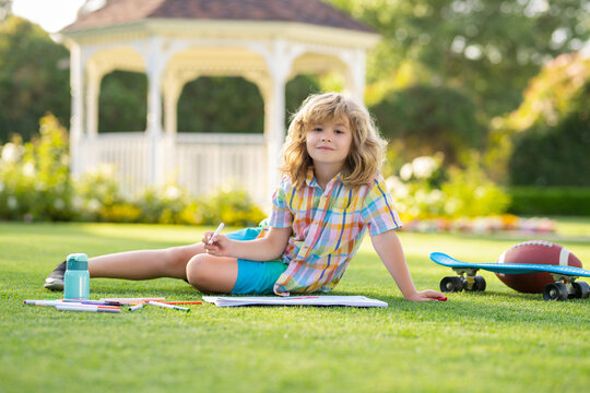 Outdoor kid play and draw craft artwork homework. Cute child boy with pencil writing on notebook outdoors. Kids outdoor learning and education concept. Summer vacation homework.