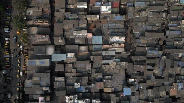 Top down aerial view of Dharavi slums next to busy road in Mumbai, Maharashtra, India. Dharavi is considered to be one of the largest slums in the world and the largest in Asia. 