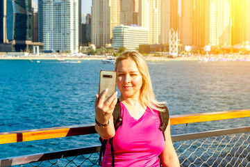 Happy girl traveler taking selfie photo for social networks in modern Finance center and bay area. Student and Tourist Blogger lifestyle concept