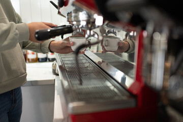 Cropped barista using coffee machine to prepare espresso