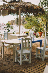 Terrace with white wooden tables and chairs and palm trees