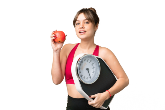 Young girl over isolated chroma key background with weighing machine and with an apple