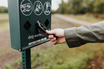 Adult female reaches for dog waste clean up bag while on walking trail