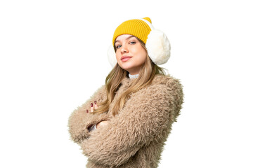 Young girl wearing winter muffs over isolated chroma key background with arms crossed and looking...