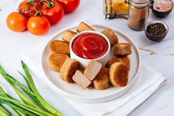 chicken nuggets in a plate on a light background, tomato sauce, 