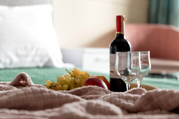 Bottle of wine and fruits on a tray on the bed