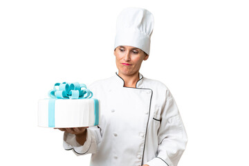 Middle-aged chef caucasian woman with a big cake over isolated background with sad expression