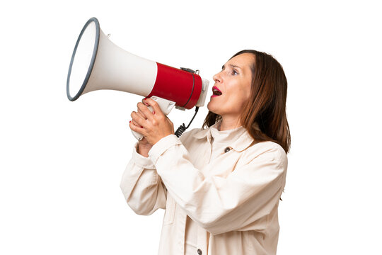 Middle-aged caucasian woman over isolated background shouting through a megaphone to announce something in lateral position