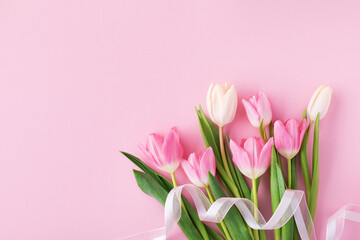 Spring tulip flowers with ribbon on pastel pink background top view. Greeting card for International Women Day, Mother day. Flat lay.