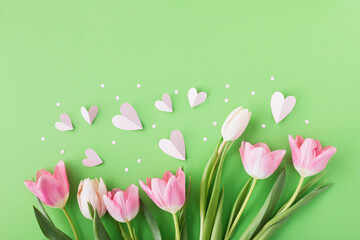 Spring tulip flowers with pink hearts on pastel background top view. Greeting card for International Women Day, Mother day. Flat lay.