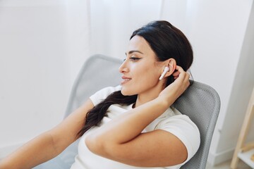 Woman listening to music on headphones at home on a chair, a smile and a good mood, a meditation to relieve stress