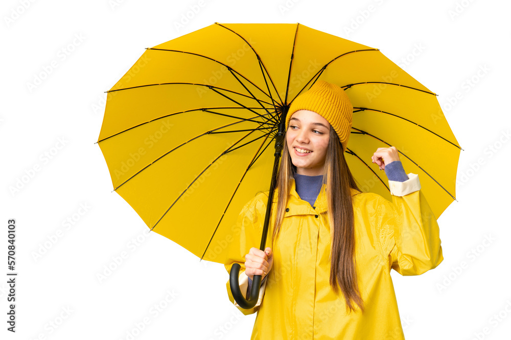 Sticker Teenager girl with rainproof coat and umbrella over isolated chroma key background celebrating a victory