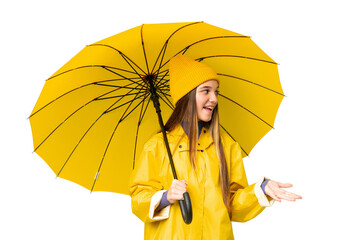 Teenager girl with rainproof coat and umbrella over isolated chroma key background with surprise expression while looking side © luismolinero