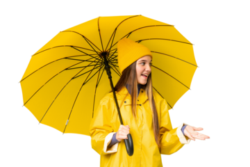 Teenager girl with rainproof coat and umbrella over isolated chroma key background with surprise expression while looking side