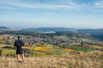 Vue de dos d'un homme sportif regardant un panorama de vigne en automne. Un coureur faisant une pose devant un paysage viticole automnal. Admirer le vignoble de Bourgogne