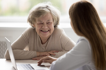 Happy positive older patient visiting geriatrician, consulting doctor in clinic office, discussing...