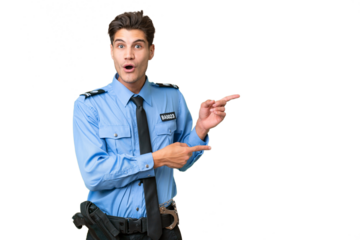 Young police man over isolated background surprised and pointing side