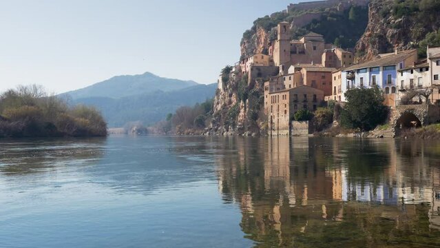 Old town of miravet with the templar castle on the top and the ebro river flowing quietly on a sunny day