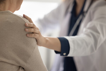 Hand of geriatrician doctor touching shoulder of elderly patient woman, giving empathy, comfort,...