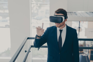 Amazed male office worker in suit being excited while trying out VR glasses