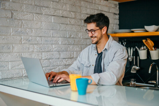 Young Focused Casually Clothed Businessman Working From The Comfort Of His Home Office Setup.