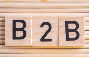 B2B letters drawn on a wooden block on a wooden table background. Business to Business. Copy space.