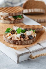 Sandwich with baked fish (tuna or salmon) with black olives, Feta cheese and parsley on rye bread. Mediterranean seafood breakfast.   Selective focus - 570847902