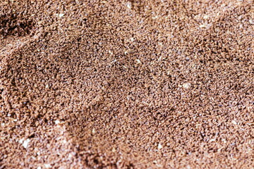The grains of ground black coffee are very close. Close up ground coffee background. Brown coffee powder texture extreme closeup photo