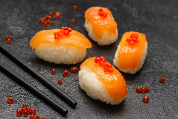 Sushi with salmon and red caviar, chopsticks.
