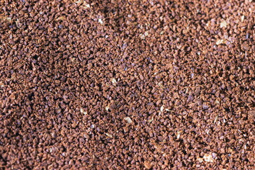 The grains of ground black coffee are very close. Close up ground coffee background. Brown coffee powder texture extreme closeup photo