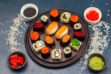 Different types of sushi on a round board. Rice is scattered on the table.