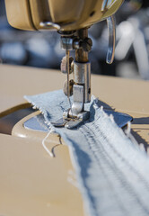 Sewing machine makes a seam on fabric. Sewing process close-up. The tailor works on a sewing machine. Selective focus.