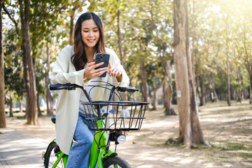 Young asian woman using smart phone on a bicycle. technology and lifestyle concept.