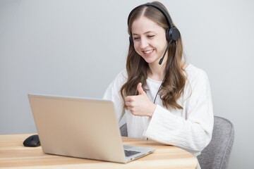 beautiful girl works at home with laptop in white sweater and shows like