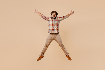 Fototapeta na wymiar Full body exultant young Indian man wears brown shirt casual clothes jump high with outstretched hands legs isolated on plain pastel light beige background studio portrait. People lifestyle concept.