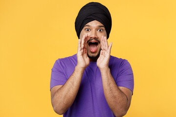Devotee Sikh Indian man ties his traditional turban dastar wears purple t-shirt scream sharing hot...