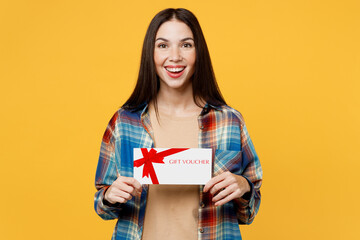 Fototapeta premium Young surprised shocked caucasian woman wear blue shirt beige t-shirt hold gift certificate coupon voucher card for store isolated on plain yellow background studio portrait. People lifestyle concept.