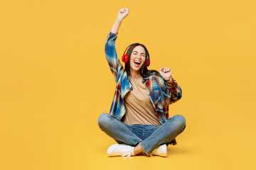 Full body young happy smiling cheerful woman wear blue shirt beige t-shirt do winner gesture listen to music on headphones isolated on plain yellow background studio portrait People lifestyle concept