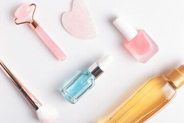 Beauty and personal care accessories on white texture background, closeup. Face roller, nail and hair care products, makeup brush.