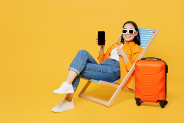 Young woman in summer clothes sit in deckchair use blank screen mobile cell phone isolated on plain...