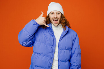 Young smiling happy fun man with long curly hair wears hat purple ski padded jacket casual clothes doing phone gesture like says call me back isolated on plain orange red background studio portrait. © ViDi Studio
