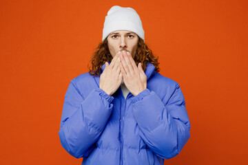 Young shocked scared sad astonished man with long curly hair wear hat purple ski padded jacket...
